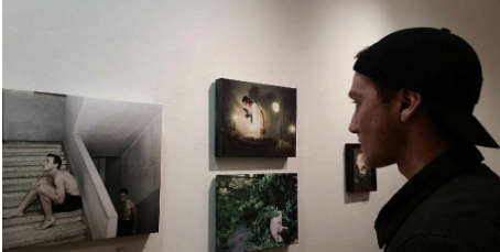 Life imitates art-- 2015 alumni Omar Taweh observes his photography on the walls in the Tunxis Community College Art Show.