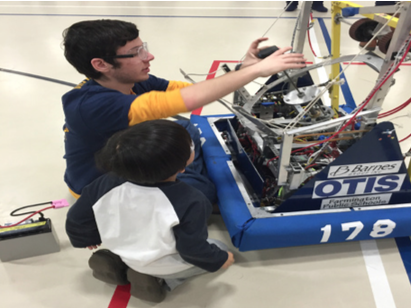 Shooting for inspiration--Senior Matt Scalzo works with an elementary school student showing him all of the parts of Captain Falcon, the team’s 2014 robot, in addition to how the robot functions by punching the giant ball to score points in the game. 