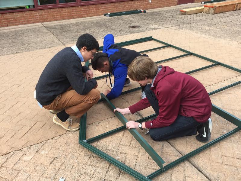 Busy building-- Sophomores Nicholas Rossitto, Jack Pelham and junior Josiah Walker build the structure to one of the four walls of the new greenhouse. Students in the Principles of Engineering classes hope to finish the project come springtime.