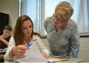 Preparation partner-- Special services paraprofessional Kathy Hancock reviews the pre-discussion questions of junior Julia Cohn in English teacher Jim Carter’s sixth period American Literature class. Hancock plans to return as a volunteer next year following her retirement.