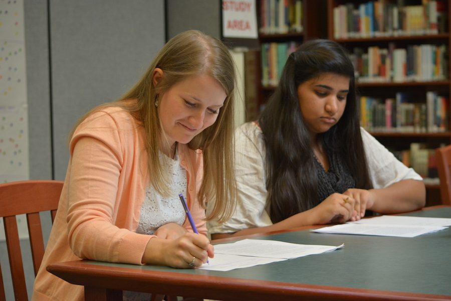 English teacher Kaitlin McIntyre and sophomore Nazish Shakeel look over student writing.
