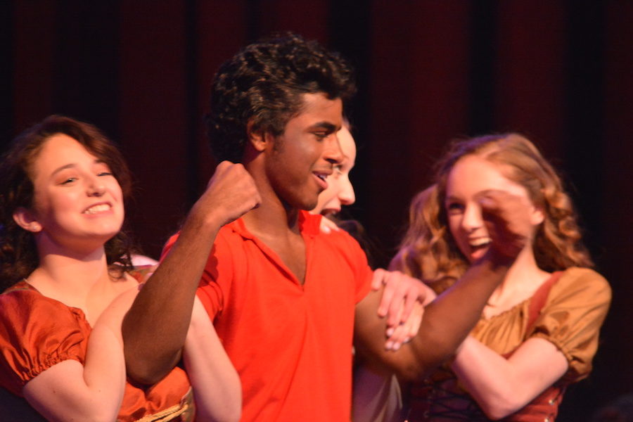 Arms of steel-- Senior Ashish John (Gaston) shows off his muscles to his admirers, junior Rebekah Moses (Silly Girl), junior Sarah Rahmig (Silly Girl) and sophomore Quinn Mahoney (Silly Girl). The girls try to swoon him into marrying one of them instead of senior Catherine Mackay (Belle).