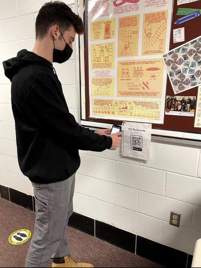 Scanning-- Senior Ricky Podgorski scans a new QR code to check into the bathroom. The codes were added outside of every bathroom in the school in order to improve contact tracing. 
