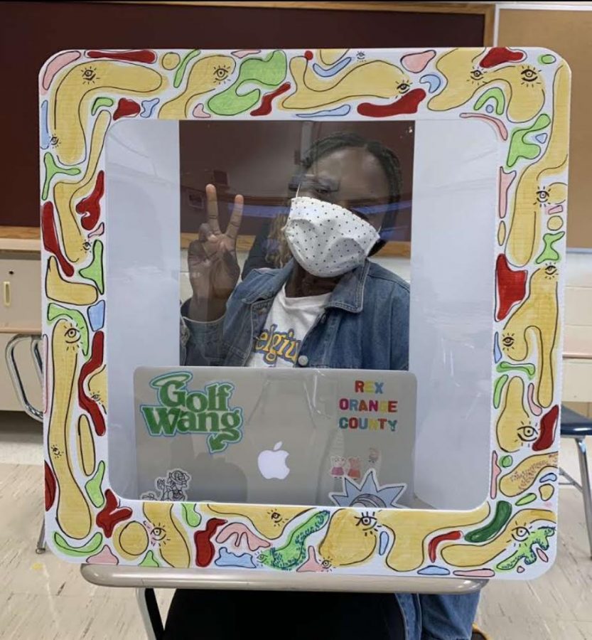 Pose for a picture -- Senior Mercy Adekola sits at her desk personalized safety shield. Senior Lindsay Fielder decorates her classmates shields to bring art into classrooms. 