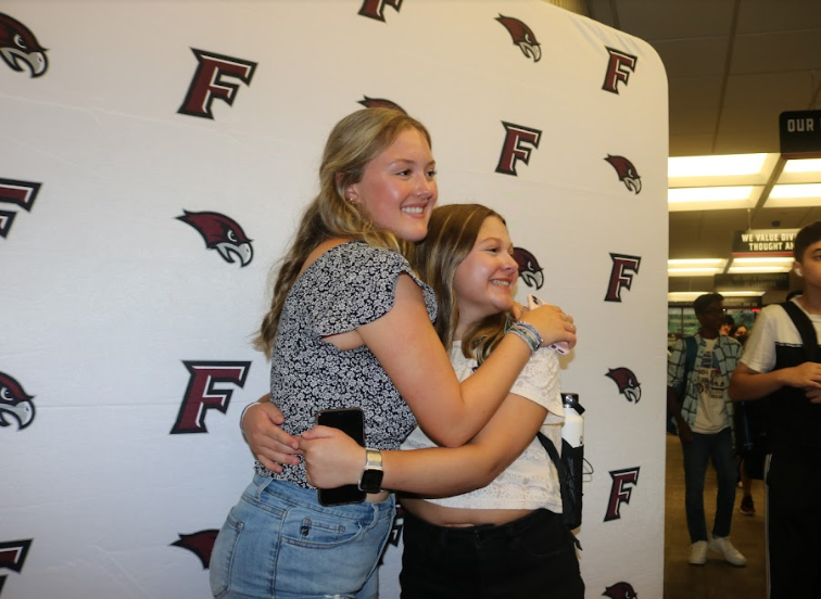 Back to school-- Briella Rich (left) and Addie Rock (right) take a photo on the glamourous riverhawk red carpet. On August 29, students returned to FHS for their first day of school and were photographed on red carpets at both student entrances.